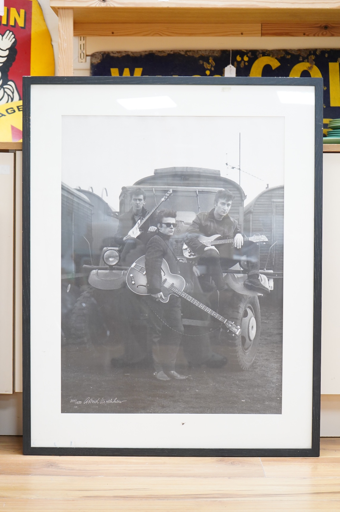 A framed and mounted black and white photograph of The Beatles by Astrid Kirchherr, showing John Lennon, George Harrison and Stuart Sutcliffe posing with guitars in front of a Land Rover, limited edition 341/500 and sign